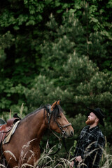 cowboy man with red beard in hat with horse close-up, friendship with animal