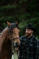 cowboy man with red beard in hat with horse close-up, friendship with animal