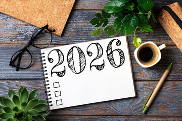 New year resolutions 2026 on desk. 2026 goals list with notebook, coffee cup, plant on wooden table. Resolutions, plan, goals, action, checklist, idea concept. New Year 2026 resolutions. Copy space