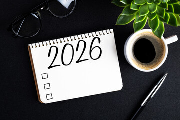 2026 New year resolutions on desk. 2026 goals list with notebook, coffee cup, plant on black table. Resolutions, plan, goals, action, checklist, idea concept. New Year 2026 resolutions. Copy space