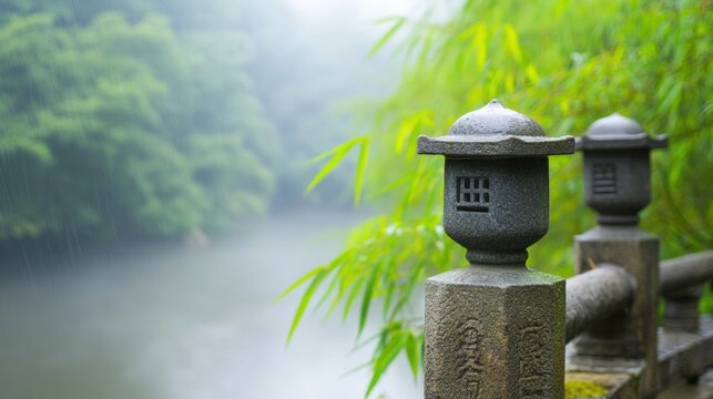 Stone lanterns beside misty lake with green foliage in background nature scene