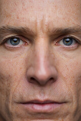 Fototapeta premium Close-up portrait of a man's face with blue eyes, showing skin texture, wrinkles, and a serious expression