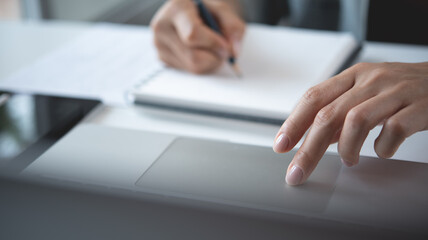 Woman using laptop computer searching ideas and making a note on notebook. Business woman working...