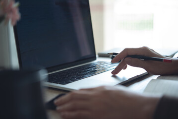 Closeup, person using laptop computer on office table. Business woman planning event schedule. Student studying online and taking note, e-learning