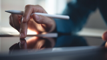 Close up, business man working on digital tablet, touching on the screen, reading e-document before signing with stylus pen. Graphic designer using graphic tablet and electronic pen