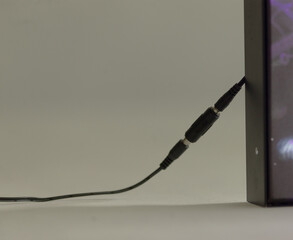 This image shows a closeup of a black audio cable connected to a device, highlighting tech...