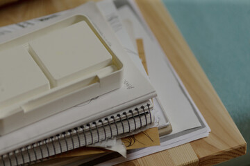 An untidy and cluttered arrangement of various notebooks and papers is scattered across the surface...