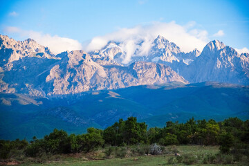 Obraz premium Snow - Capped Mountains with Clouds and Greenery