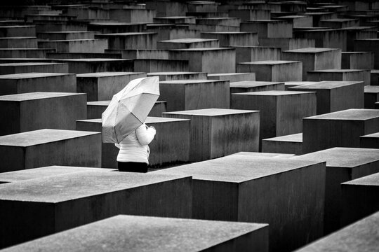 Mujer con paraguas paseando por el Memorial al Holocausto en Berl&iacute;n