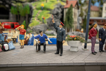 Obraz premium Miniature railway worker giving instructions to a seated figure on a platform