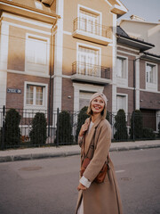 Beautiful young woman in coat walking around european city