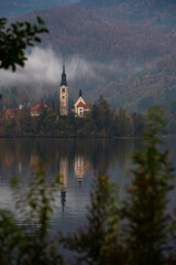 Assumption of mary pilgrimage church on lake bled, surrounded by mountains and colorful autumn foliage, in slovenia
