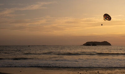 Sunset parasailing adventure over the ocean near a coastal island