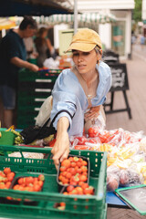 Woman wear cap, shirt and choose strawberry basket on local street market. Concept of eco food....