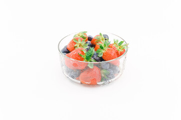 ciotola in vetro con frutti freschi da coltivazione biolagica, sfondo bianco