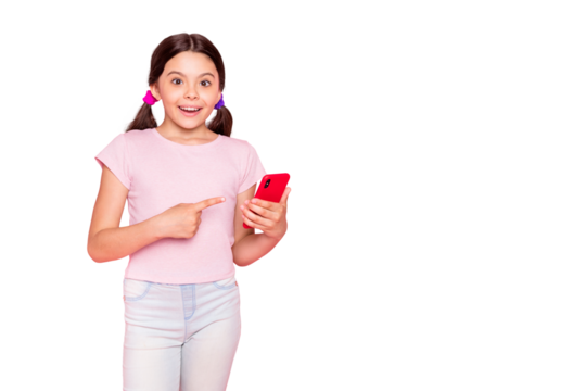 Portrait of excited kid with ponytails pigtails holding gadget screaming indicating dressed trendy stylish t-shirt pants trousers isolated over pink background