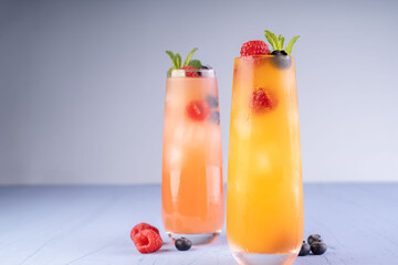 refreshing fruit-infused summer cocktails in tall glasses with mint garnish and berries on a cool blue surface, creating a vibrant, inviting atmosphere for social gatherings, contrast, aesthetic
