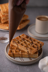 photo Delicious Waffles Topped with Rich Chocolate Syrup: A Savory Breakfast or Dessert Treat Paired Perfectly with a Hot Cup of Coffee in a Cozy Setting to Enjoy