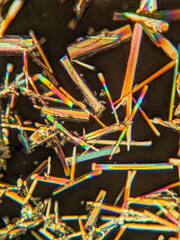 Needle-like crystals under polarized microscope showing vivid birefringence