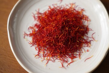 Fototapeta premium A bowl filled with red saffron threads on a wooden table.