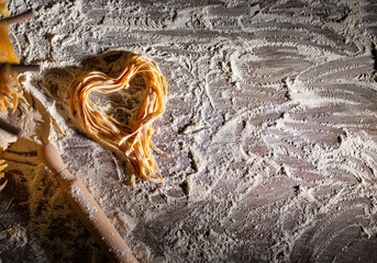 Heart shaped noodles on floured kitchen table top view cooking background with copy-space