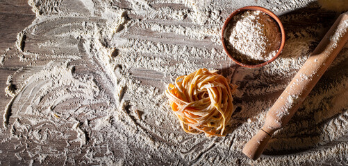 Portion of homemade noodles on floured kitchen table top view cooking background with copy-space