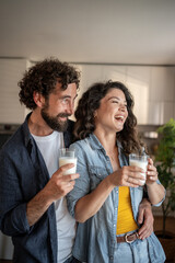 Happy couple drinking milk and laughing together in kitchen