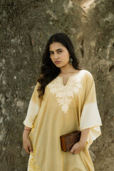Women weaing mustard gown posing in front of a tree, out in the nature.