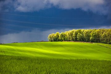 Splendid green hills in the countryside on a stormy day: the sun light comes through and creates waves of light and shadow.