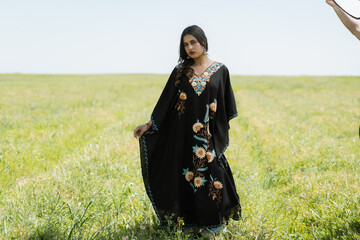 Photshoot for Kaar kash Women wearing black Kaftan dress posing in a mustard field