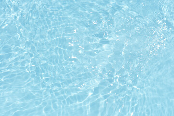 Blue water with ripples on the surface. Defocus blurred transparent blue colored clear calm water surface texture with splashes and bubbles. Water waves with shining pattern texture background.