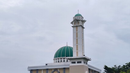 Prominent Mosque with Green Dome and Minaret Under Cloudy Sky in Jakarta