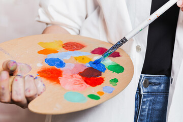 Artist Mixing Paint on Wooden Palette With Brush