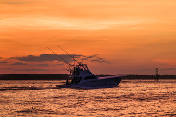 deep sea fishing boat headed out at sunset
