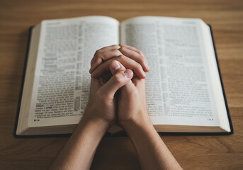 Clasped Hands in Prayer Over an Open Bible on Wooden Table &ndash; Overhead Shot Symbolizing Faith, Devotion, and Quiet Reflection