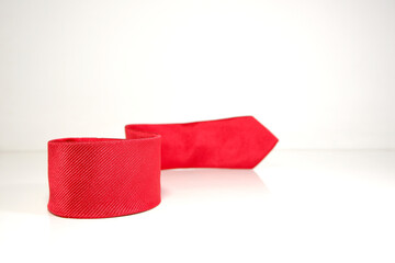 Fototapeta premium red tie rolled on white background closeup view selective focused 