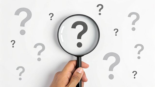 Hand Holding Magnifying Glass Focusing on Question Mark with Multiple Inquiry Symbols on White Background &ndash; Concept of Curiosity, Research, and Problem Solving