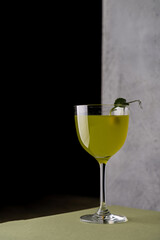 At a stylish restaurant, a vibrant green drink is displayed in a chic glass. The exquisite...