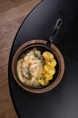 Savory dishes are elegantly presented on a wooden platter, showcasing a delightful medley of flavors with golden potatoes and fragrant herbs at a charming restaurant setting