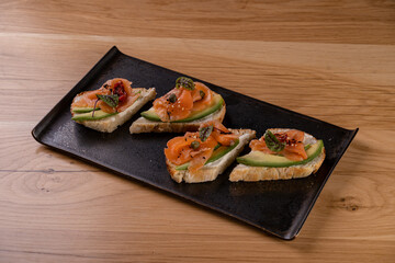 A selection of elegant gourmet appetizers featuring smoked salmon atop crisp bread with fresh avocado, perfect for an intimate dining experience. Ideal for food lovers