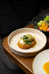 Delight in a beautifully crafted gourmet dish showcasing a crispy base topped with creamy goodness, garnished with fresh greens. Accompanied by a refreshing salad of colorful vegetables