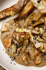 A tantalizing blend of sautéed mushrooms atop a creamy sauce, accompanied by crunchy bread. This sumptuous dish exemplifies the artistry of contemporary gastronomy and flavor exploration