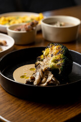 Exquisite culinary creations adorn the table, showcasing perfectly charred broccoli drizzled with a rich sauce. Surrounding it are savory sides, creating a feast for the senses