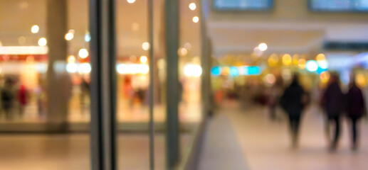 Blurred view of people inside a building with glass doors and lights.premium shopping center background for poster, banner and flyer background