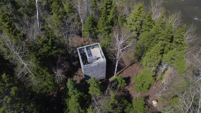 Aerial view of a wooden observation tower discreetly positioned along a forest hiking trail in Mitis River Park, Quebec, Canada.