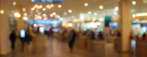 Blurred interior view of a shopping mall with people walking and lights.premium shopping center background for poster, banner and flyer background