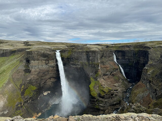 Obraz premium panoramic view of Haifoss and Grannifoss plummeting off a flat treeless plateau into a canyon showing different geological layers of stone