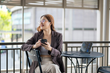 Fototapeta premium A woman is sitting at a table with a laptop and a cell phone