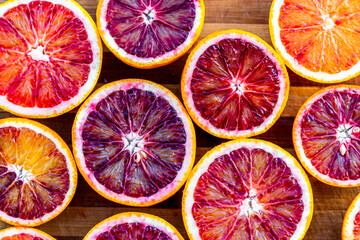 Red blood halved oranges close up on a wood background. Top view. Flat lay of fresh orange citrus...
