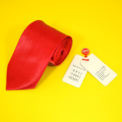 A red tie rolled on yellow background closeup view with tags